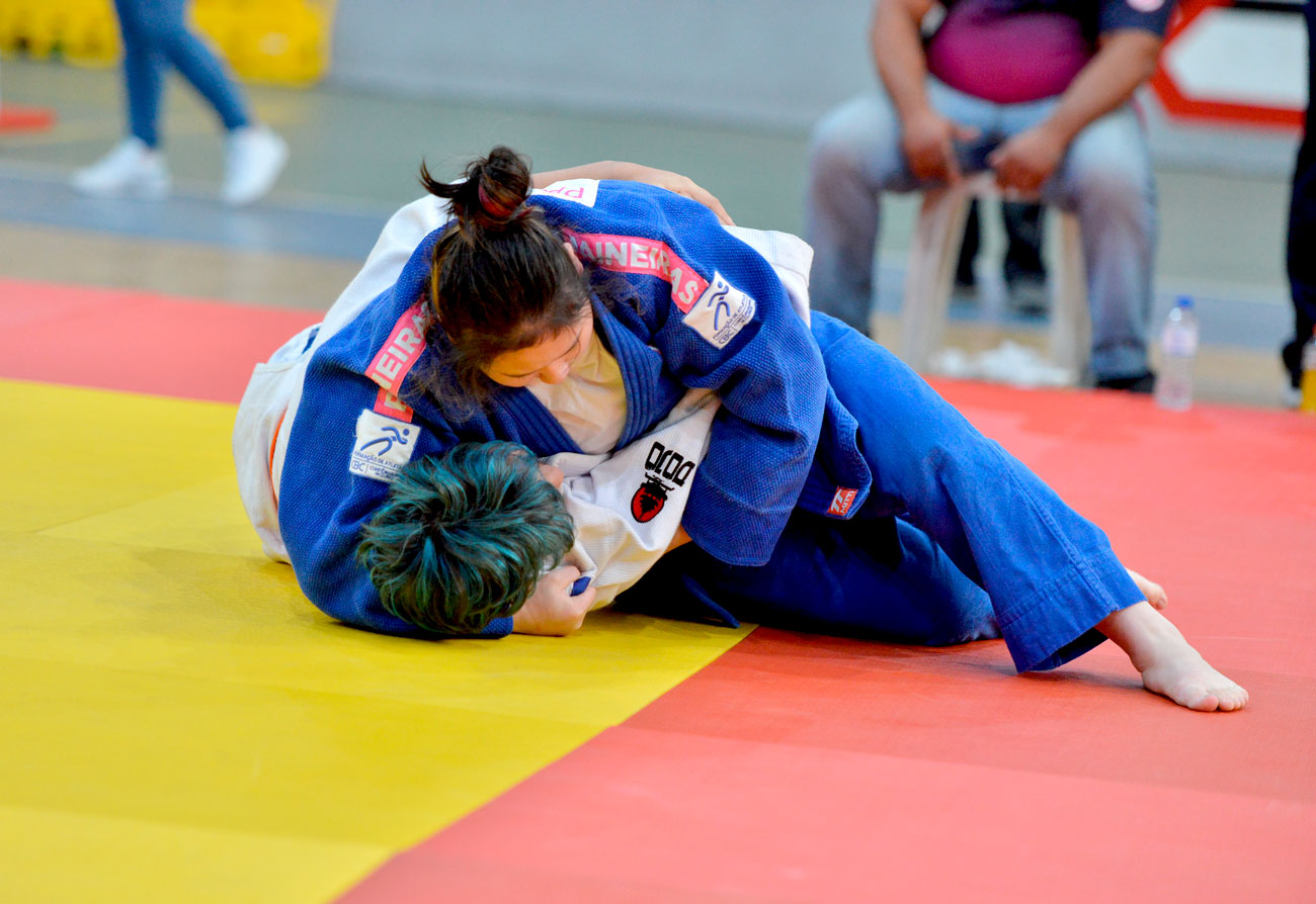 Uma mulher está competindo em um tatame de jiu-jitsu.