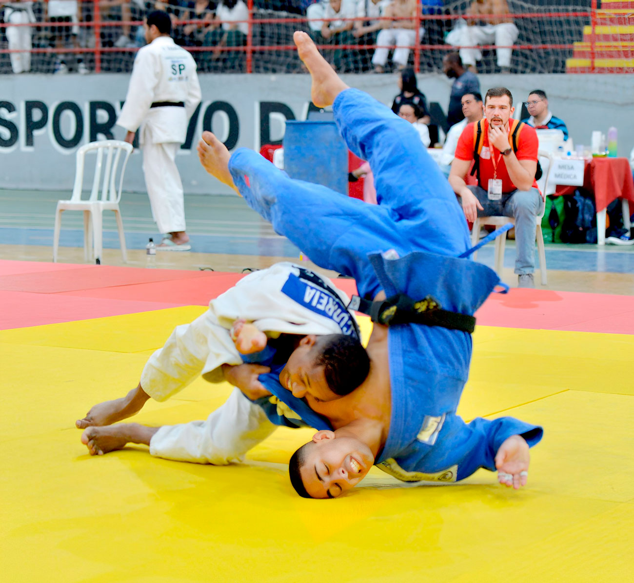 Um judoca com uniforme azul e amarelo.