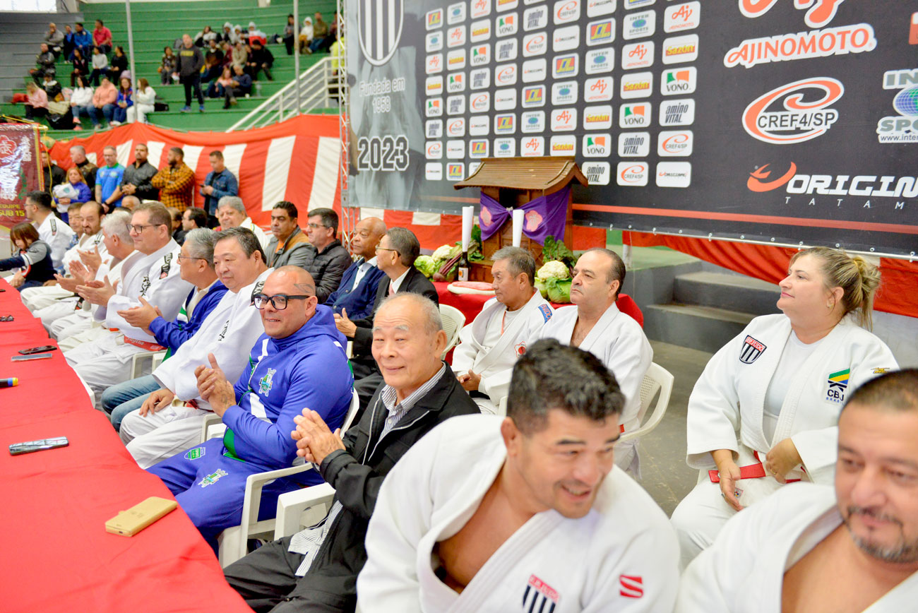 Um grupo de pessoas batendo palmas em uma mesa durante a 72ª edição do Torneio Budokan.
