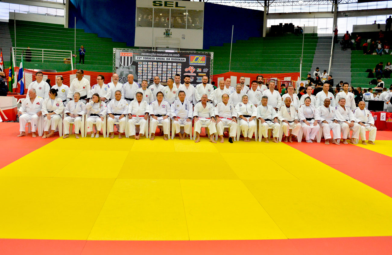 Um grupo de pessoas posando para uma tradicional foto de grupo na 72ª edição do Torneio Budokan, mostrando uma parceria transformadora.