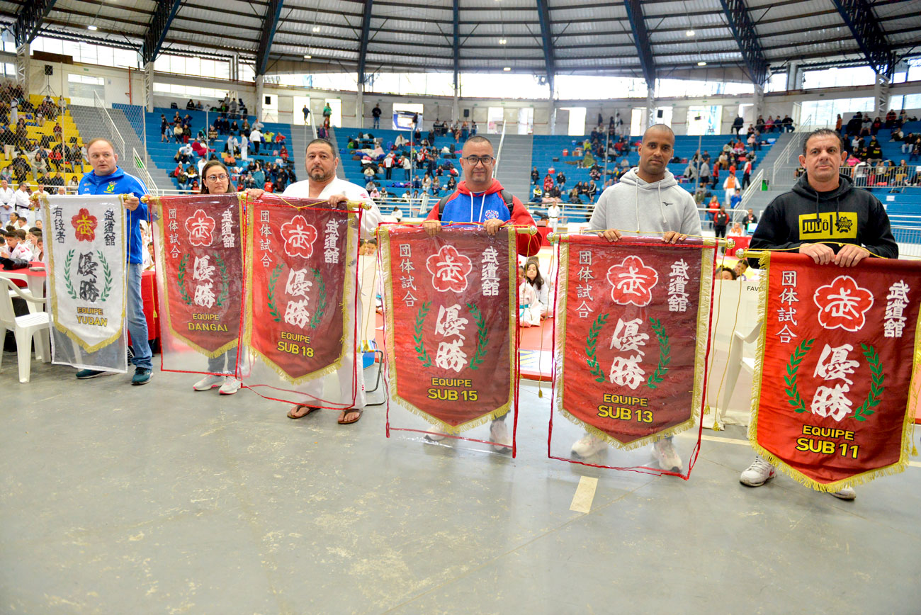 Um grupo de pessoas segurando faixas durante a 72ª edição do Torneio Budokan e o segundo ano de uma parceria transformadora, marcada por tradição e história.